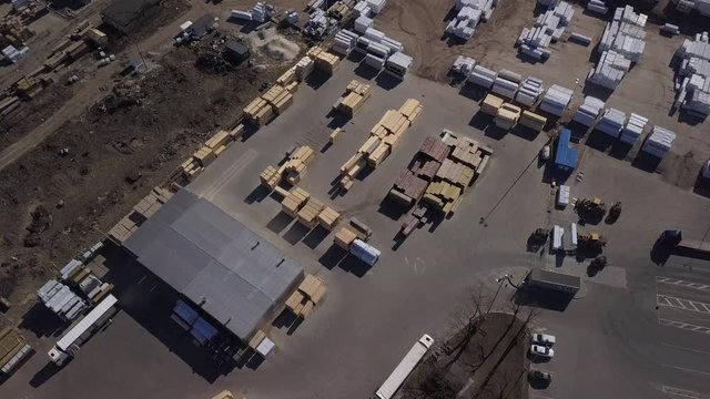 Piles and stacks of wood in a lumber yard sawmill and an outside warehouse. Aerial top down view in 4K 
