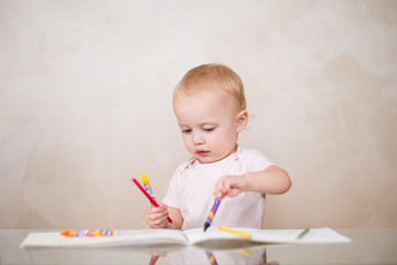little girl is ineptly drawing a line with a pencil in a sketchbook