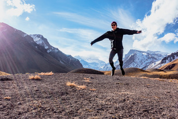 Young woman jumping mid-air in front of Mount Aconcagua, Argentina.  