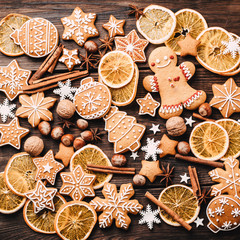 Fototapeta na wymiar Christmas vibes, celebration atmosphere. Winter composition, background made of dried orange slices, spices and gingerbread cookies, New Year greeting card