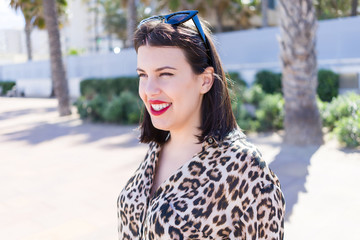 Young beautiful woman with red lips wearing sunglasses smiling happy at the street