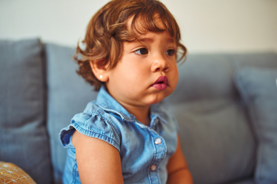 Beautiful toddler child girl wearing blue denim shirt sitting on the sofa