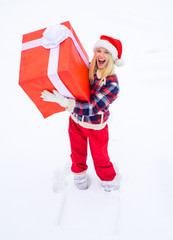 Obraz premium Big gift box. Funny woman holding a big Christmas present - full length. Happy woman in red dress having fun with big gift box isolated on a white snow background.