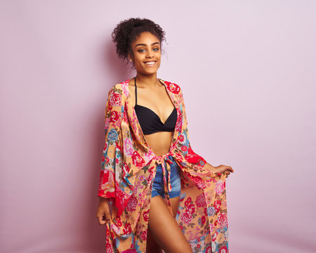 Young beautiful african american woman on vacation standing wearing bikini and colorful caftan