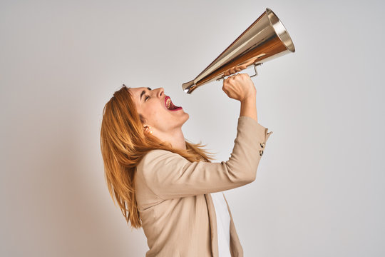 Young beautiful readhead businesswoman screaming using vintage megaphone