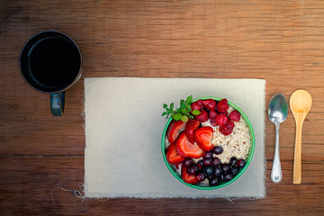 oatmeal with berries and coffee breakfast in a wooden table at the morning