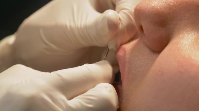 Piercing the tongue in close up view at a professional piercing and tattoo studio