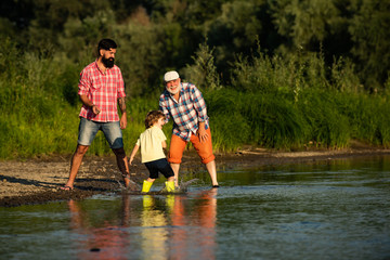 Three generation family. Skipping Stones with Dad adn Granddad. Three different generations ages: grandfather father and child son together.