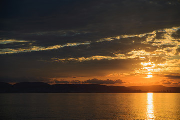 view from sea to sunset over town on sea, horizontal twilight panoramic stock photo image