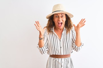 Obraz na płótnie Canvas Middle age businesswoman wearing striped dress and hat over isolated white background celebrating crazy and amazed for success with arms raised and open eyes screaming excited. Winner concept