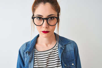 Redhead woman wearing denim shirt and glasses standing over isolated white background with a confident expression on smart face thinking serious