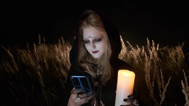 Ggirl In The Image Of Witch Uses Mobile Phone. Halloween Image.