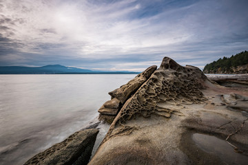 sand stone with unique formation on the edge of the island under cloudy sky near dusk