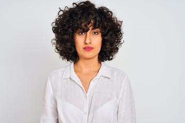 Young arab woman with curly hair wearing casual shirt over isolated white background with serious expression on face. Simple and natural looking at the camera.