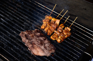 Grilled smoked pork ribs cooking on wood charcoal grill. BBQ Roast Marinated Baby Back Pork Ribs. Popular street food in Ubud, Bali, Indonesia. Delicious food and popular with tourists.