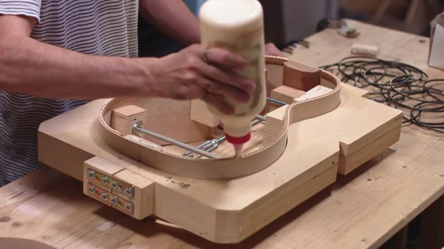 Luthier glueing side of handmade guitar