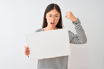 Young chinese woman wearing glasses holding banner over isolated white background annoyed and frustrated shouting with anger, crazy and yelling with raised hand, anger concept