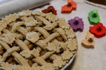 Selective Focus Closeup of a decorative unbaked pie crust with braids and autumn leaves