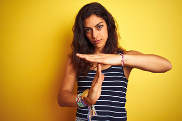 Young beautiful woman wearing striped t-shirt standing over isolated yellow background Doing time...
