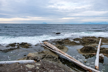 waves of waves pounding the rocky shore line on the island under overcast sky near dusk