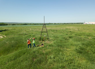 Man and Woman land surveyors a construction site. Young engineers surveyor in helmets give each other five. ..