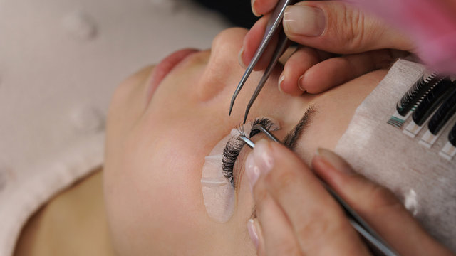 Beautiful Woman with long eyelashes in a beauty salon. Eyelash extension procedure.