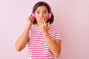 Young beautiful woman listening to music using headphones over isolated pink background cover mouth with hand shocked with shame for mistake, expression of fear, scared in silence, secret concept