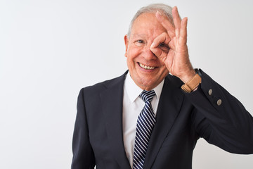 Senior grey-haired businessman wearing suit standing over isolated white background doing ok gesture with hand smiling, eye looking through fingers with happy face.