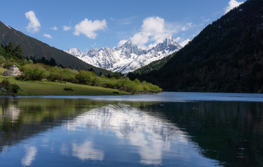 Fototapeta na wymiar Snow mountains with green hill, forest and lake in Sichuan, China