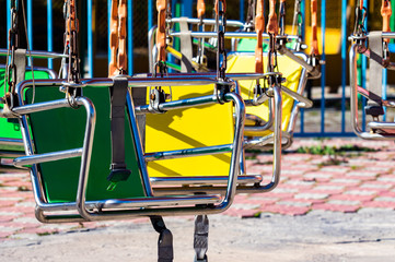 Empty carousel metal seat. Amusement park concept in a city park. Sunny day.