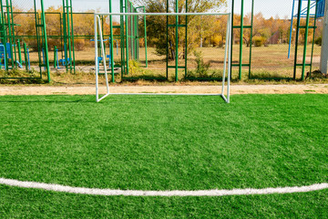 Futsal football field artificial turf on autumn nature.
