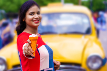 Young Indian girl enjoying ice cream on street vendor near taxi stand