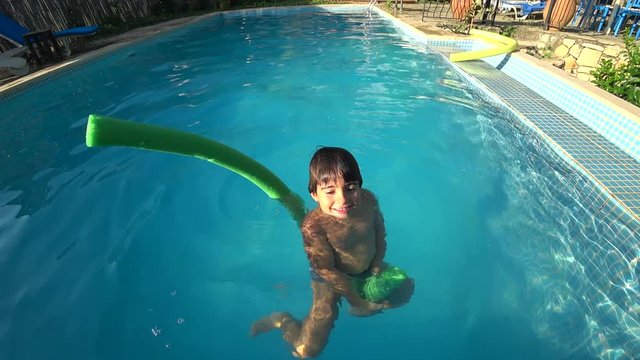 Kas, Turkey - 28th of September 2019: 4K Kid having fun with a nooddle in the countryside swimming pool