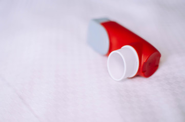 A still life of red and white asthma inhaler devise on a white background