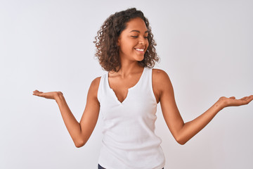 Young brazilian woman wearing casual t-shirt standing over isolated white background smiling showing both hands open palms, presenting and advertising comparison and balance