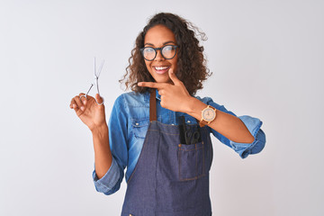 Young brazilian hairdresser woman using scissors standing over isolated white background very happy pointing with hand and finger