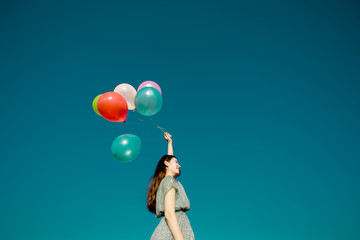 Happy asian woman playing colorful balloons on blue sky background. Freedom concept