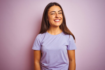 Fototapeta premium Young beautiful woman wearing casual t-shirt standing over isolated pink background winking looking at the camera with sexy expression, cheerful and happy face.