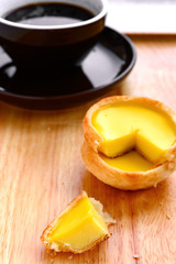 fresh egg tarts with a quarter cut out and cup of coffee on back