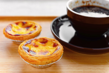 side view fresh portuguese egg tarts with cup of coffee nearby