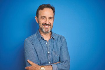 Handsome middle age senior man with grey hair over isolated blue background happy face smiling with crossed arms looking at the camera. Positive person. - Powered by Adobe