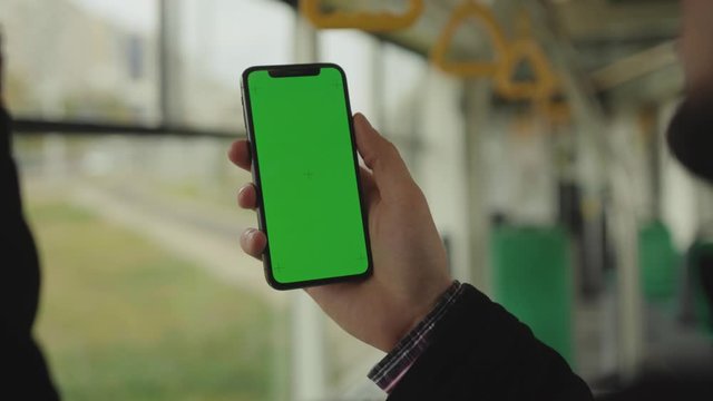 Hands uses holding a mobile telephone with a vertical green screen background tram seat people window key smartphone technology touch message display close up slow motion