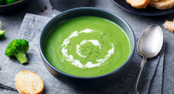 Broccoli, spinach cream soup in a bowl with toasted bread. Close up.