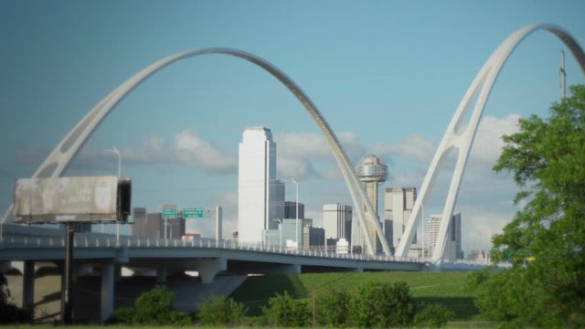 Slow ZOOM-IN - The Dallas Skyline is Framed by the Margaret McDermott Bridge with the Iconic Reunion Tower in the center. Slow moving traffic drives over the bridge on a beautiful day.