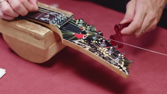 Guitar maker wrap string with a guitar peg