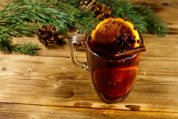 Christmas mulled wine with spices and fir tree branches and cones on wooden table
