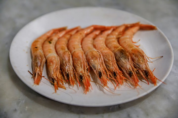 Traditional gambas a la plancha or grilled shrimp tapas being cooked on a hot plate in Madrid, Spain