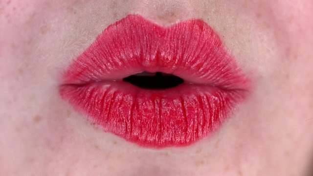 Slow motion of woman lipgloss lips kissing the camera, close up macro