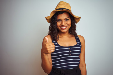Beautiful transsexual transgender woman wearing summer hat over isolated white background doing happy thumbs up gesture with hand. Approving expression looking at the camera with showing success.