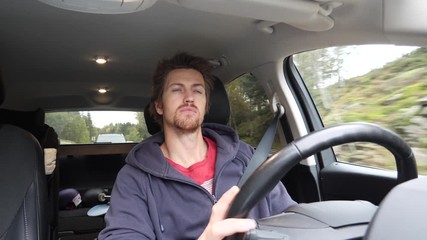 Young man driving a car in a relaxed yet cautious manor - from dashboard looking at driver